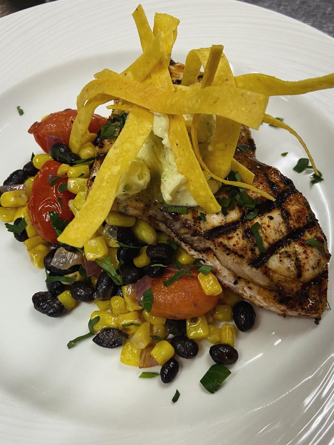 Grilled swordfish steak topped with whipped cilantro lime butter on a white plate